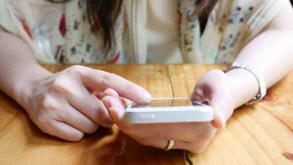近距离女人的手使用智能手机在咖啡馆