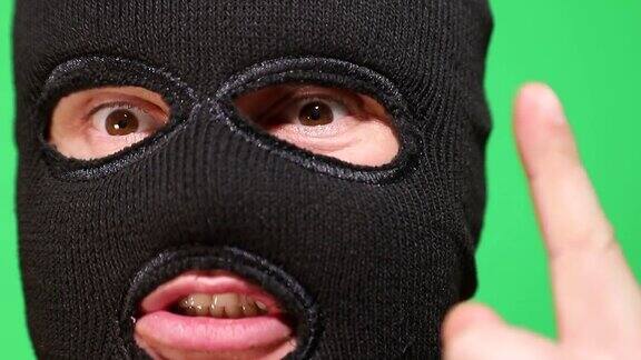 可怕的小偷或强盗戴着面具看着摄像机