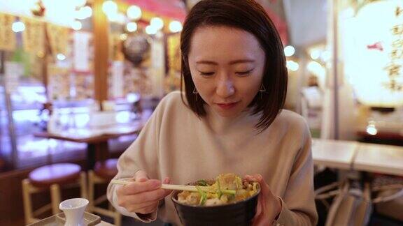 一名年轻的日本女子在居酒屋酒吧吃日式鸡肉“顿饭”