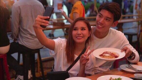 一对年轻情侣在餐厅用手机自拍