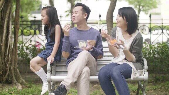 年轻的台湾家庭坐在长椅上