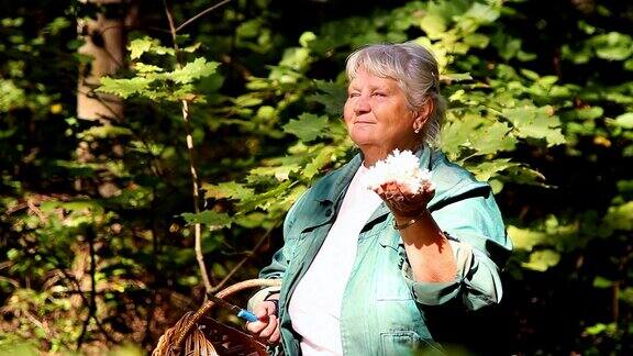 一位上了年纪的妇女在森林里展示珊瑚蘑菇