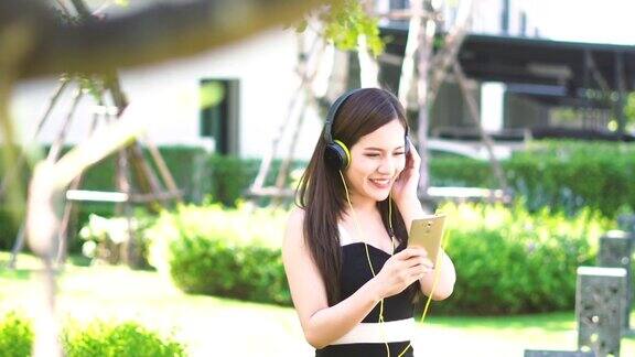 年轻的亚洲女子在花园里欣赏音乐