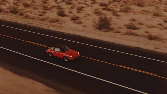 鸟瞰图红色经典汽车沿着荒凉的沙漠道路在黄昏与头灯打开