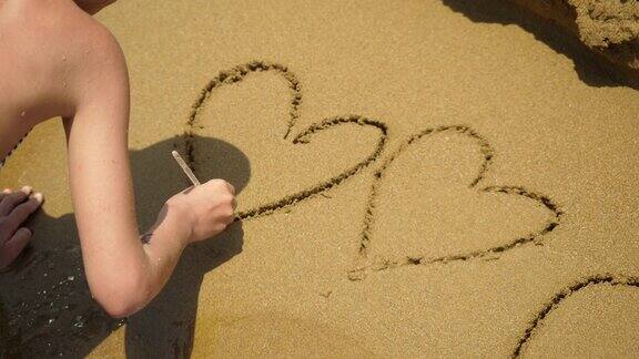 女孩在沙滩上画心形符号