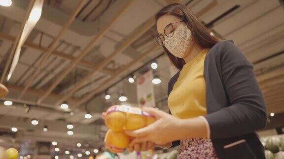 新常态生活理念新冠肺炎疫情期间妇女戴着外科口罩在超市购买新鲜食品蔬菜