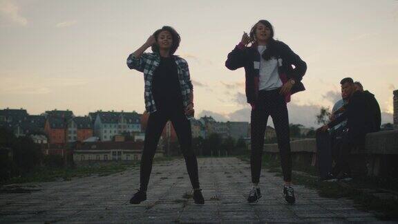 两个少女在废弃的建筑上为朋友表演现代舞