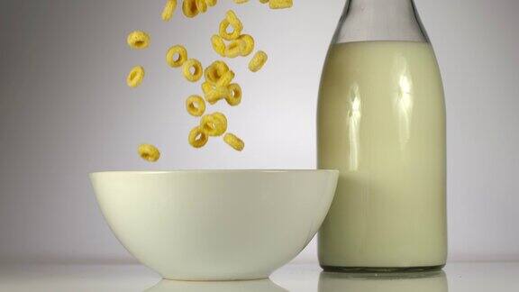慢镜头:玉米片落在桌子上牛奶旁边的白色盘子上