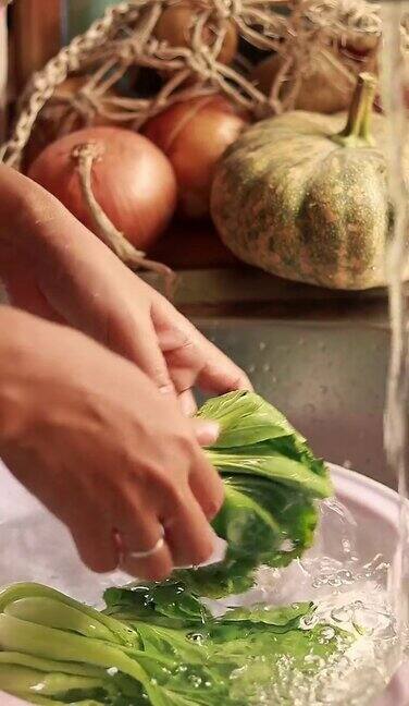 垂直视频特写双手在水槽中清洗新鲜的蒲菜