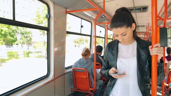 漂亮的年轻女子在电车火车上使用手机