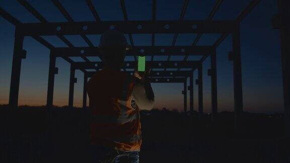 黄昏时分建筑工人在建筑工地使用智能手机