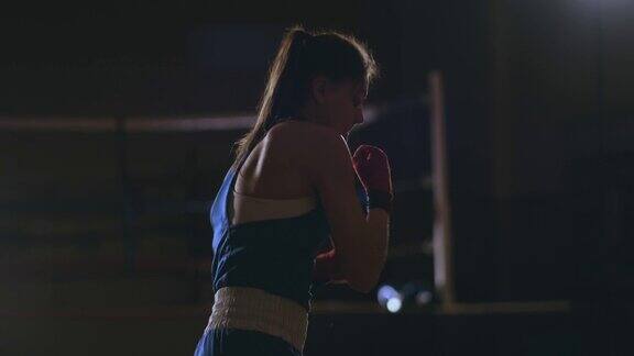 女子拳击训练在暗室与背光慢动作侧视图替身拍摄