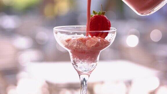 酒保在杯子里倒入冰沙和草莓