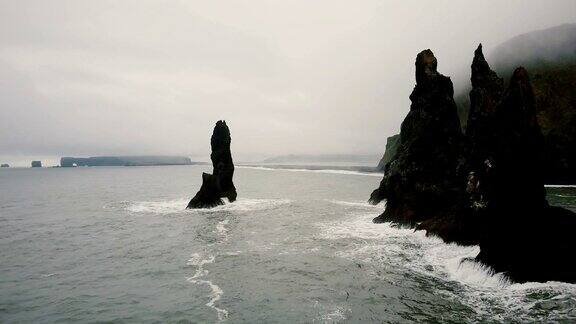 鸟瞰图巨怪脚趾岩石和冰岛的黑色火山海滩直升机离悬崖很近