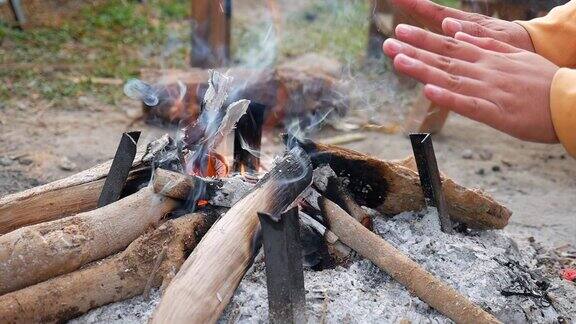 一名男子在露营篝火旁暖手