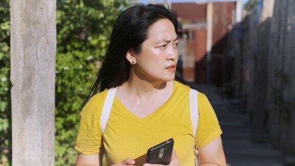 慢镜头亚洲女子关掉手机走在木桥上在阳光明媚的日子里游览当地城市