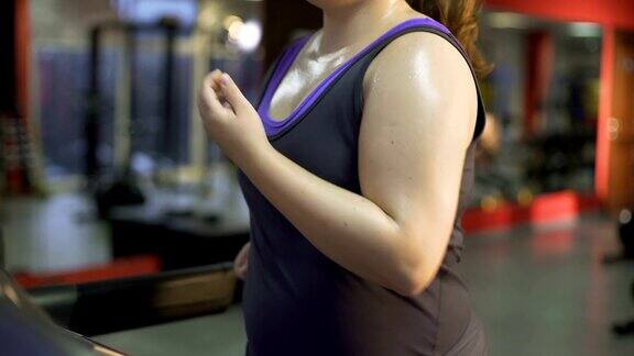 强壮的超重女性努力减肥在跑步机上出汗