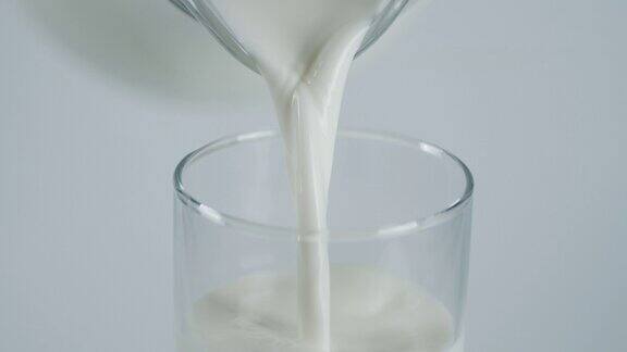 牛奶从罐子倒进玻璃杯里