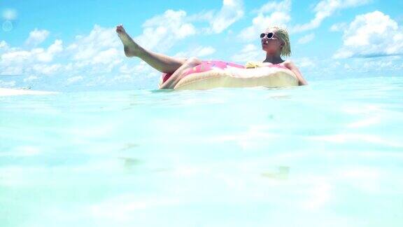 一个金发女人漂浮在马尔代夫的海洋里