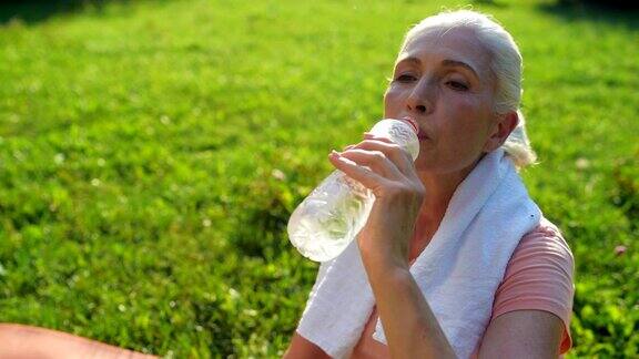 高兴的老年妇女在运动后喝水
