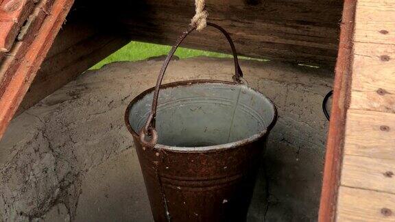挂满水的金属桶挂在农村的一口井里