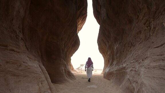 一名沙特男子穿过岩石之间的通道