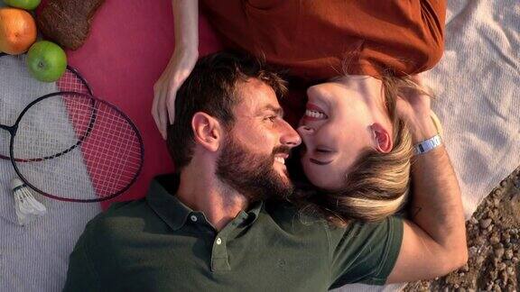幸福的年轻夫妇躺在野餐毯上分享彼此的深情庆祝他们的爱情