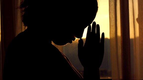 日落时在窗前祈祷的女人