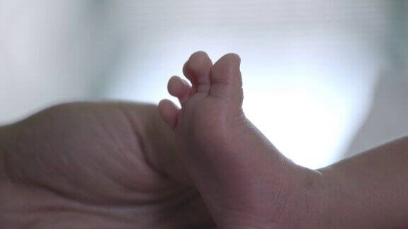 当她的宝宝在温柔和爱中睡觉时妈妈靠近新生儿的脚幸福的家庭