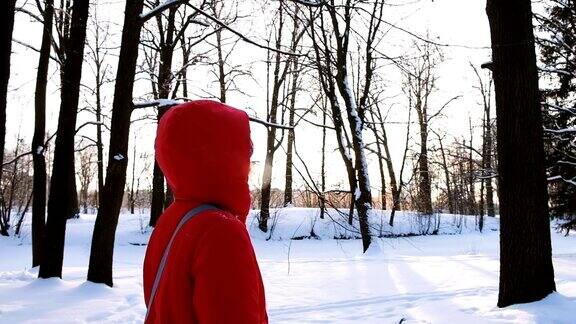 一个穿着红色羽绒服的女孩在冬日的晚霞中漫步慢镜头