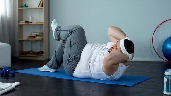 大块头的年轻人在做仰卧起坐腹部运动肌肉无力