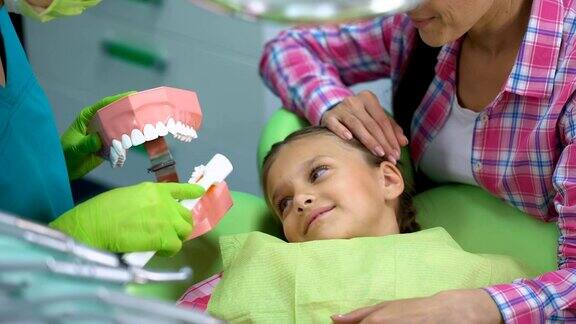 友善的儿科牙医向孩子讲解如何正确刷牙