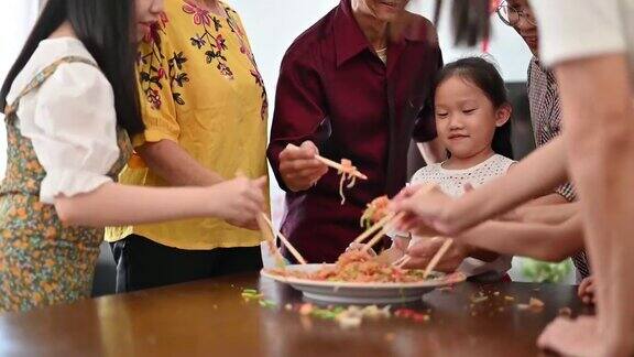一个亚洲家庭在团圆饭上用传统食物“生鱼”庆祝中国新年