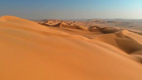 空中拍摄的沙漠沙丘在日落时分飞过一望无际的黄色沙丘