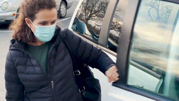 成熟的女人戴着防护面罩从车里出来