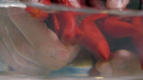特写男子的手被清洗新鲜的热红辣椒干净的水在玻璃花瓶素食者的健康营养食品也适合辛辣食物或菜肴电影4k