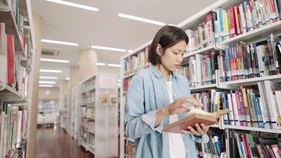 亚洲女大学生在大学校园图书馆的藏书与课本阅读