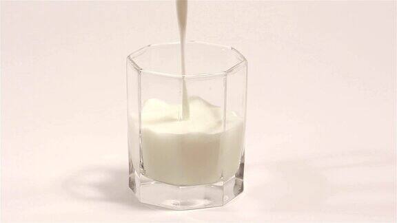 牛奶在白色背景的透明杯中流动