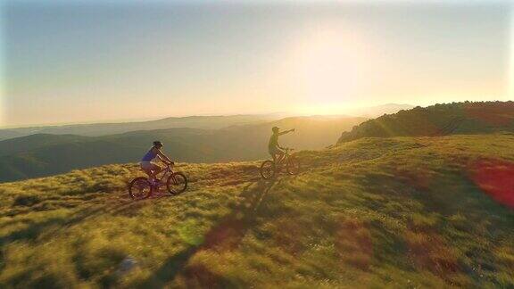摄影:一对活跃的游客夫妇骑着自行车从长满草的山坡上飞驰而下