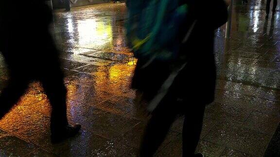 商人和上班族在雨夜潮湿的人行道上行走