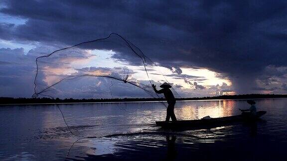 清晨渔民在木船上撒网捕鱼