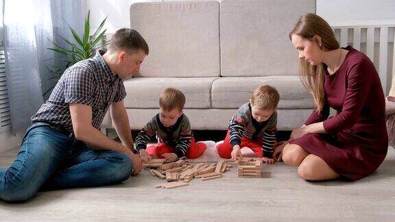 家庭妈妈爸爸和两个双胞胎兄弟一起在地板上玩积木