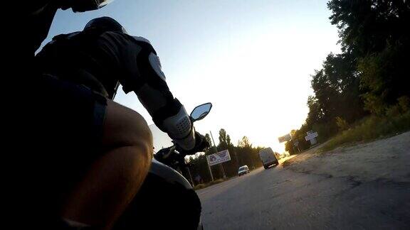 日落时分两名男子骑着摩托车高速行驶在乡村公路上朋友们骑着自行车向太阳高速前进低视角Pov近距离