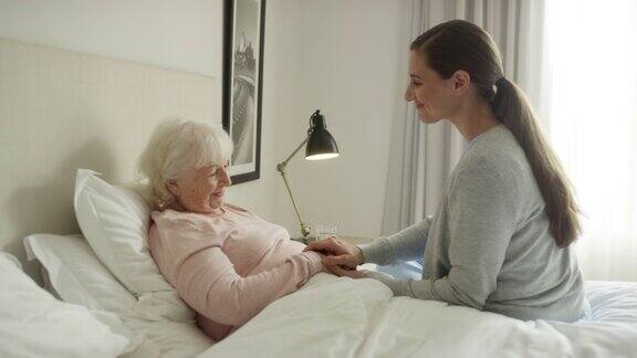 微笑的看护者牵着老年病人的手