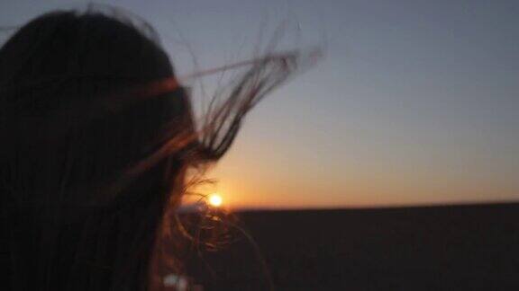 女人的头发在夕阳中随风飘动