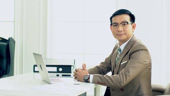 一个亚洲商人在他的办公室里对着笔记本电脑工作
