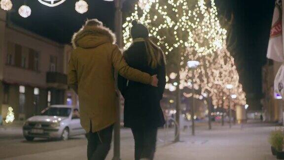 一对年轻夫妇在圣诞彩灯下散步