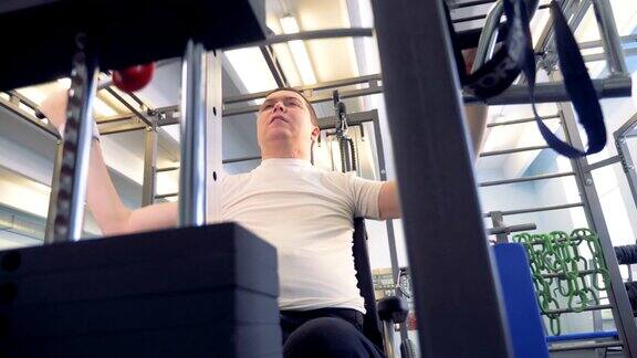 一个残疾人正在健身房练习举重器械