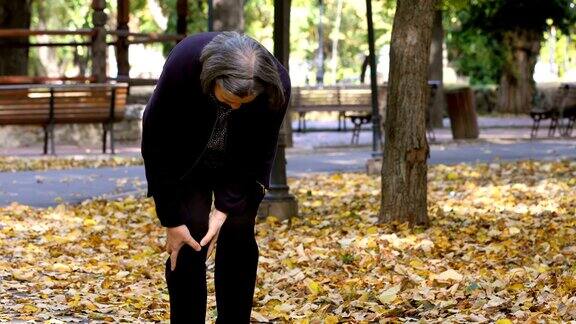 老妇人在公园散步时膝盖疼痛