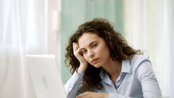 疲惫的女人一边在笔记本电脑上打字一边点头